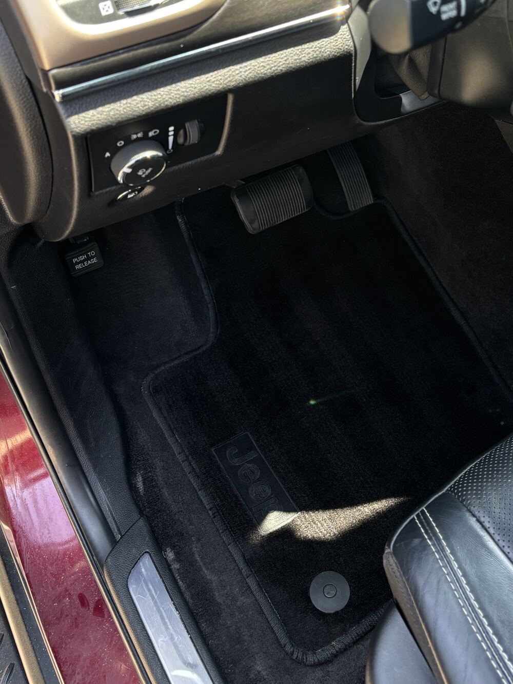 Driver-side floor after an interior detail: clean black carpet and mat