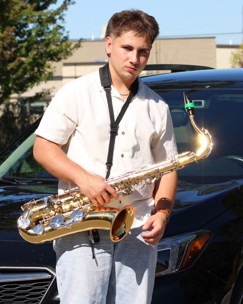 Isaac, owner of Grimy to Shiny, standing in front of a black Subaru